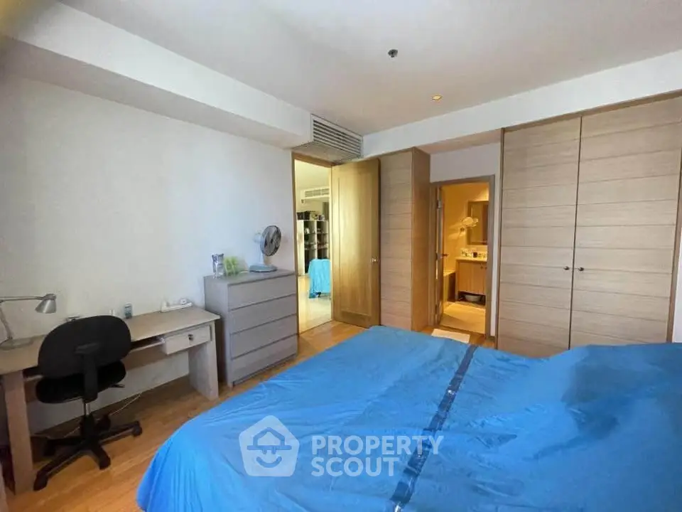 Spacious bedroom with modern furniture and ensuite bathroom in a stylish apartment.