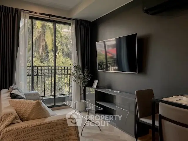 Modern living room with large TV and balcony view, featuring sleek furniture and natural light.