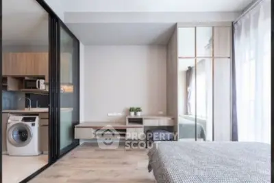 Modern studio apartment with open layout, featuring a cozy bedroom and compact kitchen with washing machine.