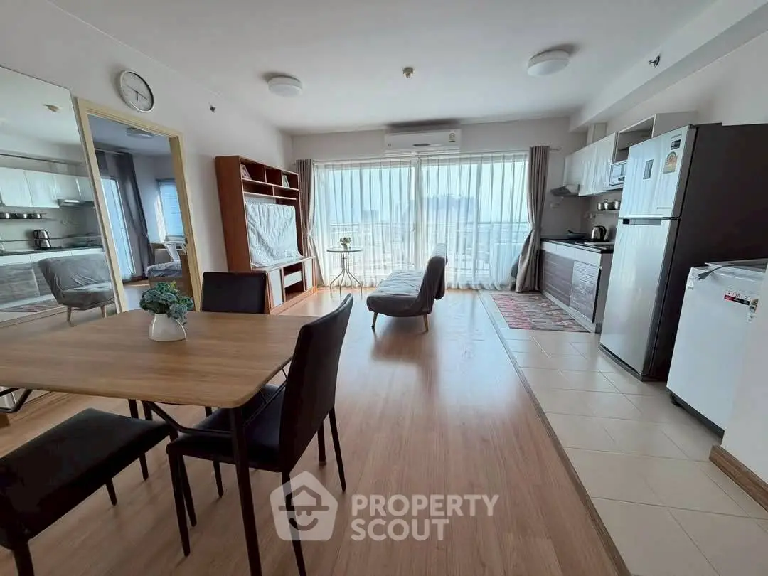 Spacious open-plan living room with modern kitchen and dining area, featuring large windows and stylish decor.