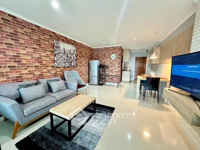 Modern open-plan living room with brick accent wall and stylish furniture