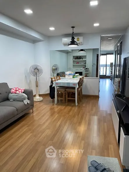 Spacious living room with wooden flooring and modern furniture in a cozy apartment.