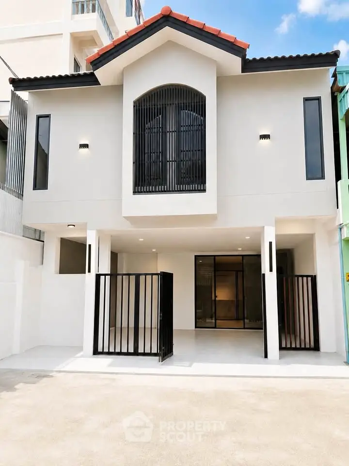 Modern two-story house with gated entrance and large windows, showcasing contemporary architecture.