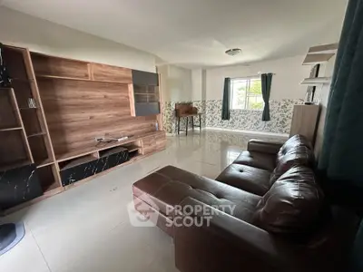Spacious living room with modern leather sofa and stylish wooden shelving unit.