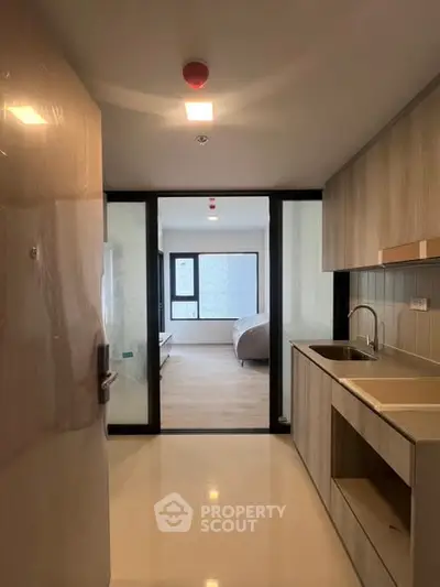 Modern kitchen with sleek cabinetry and open layout leading to a bright living area.