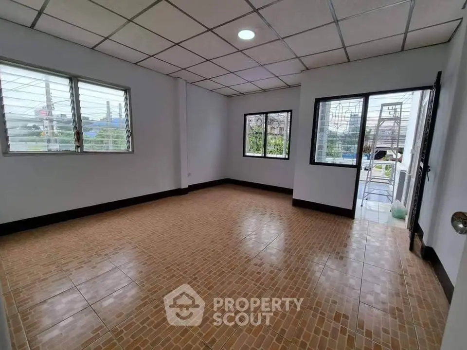 Spacious empty room with tiled floor and large windows offering natural light.