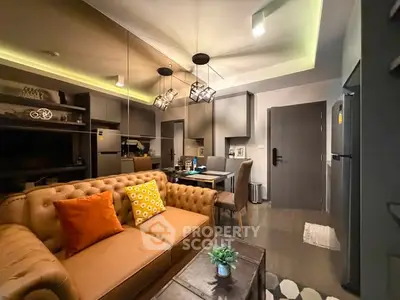 Modern living room with stylish decor and open kitchen layout, featuring cozy seating and contemporary lighting.