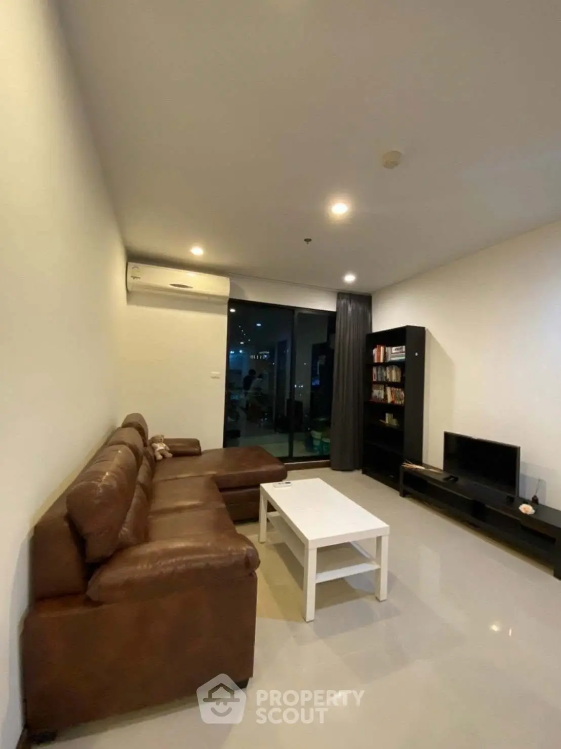 Modern living room with leather sofa, sleek TV stand, and large window for natural light.