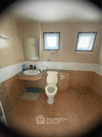 Spacious bathroom with modern fixtures and natural light from two windows.
