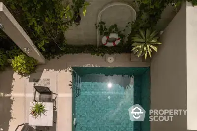 Charming private pool with lush greenery and stylish outdoor seating area, perfect for relaxation.