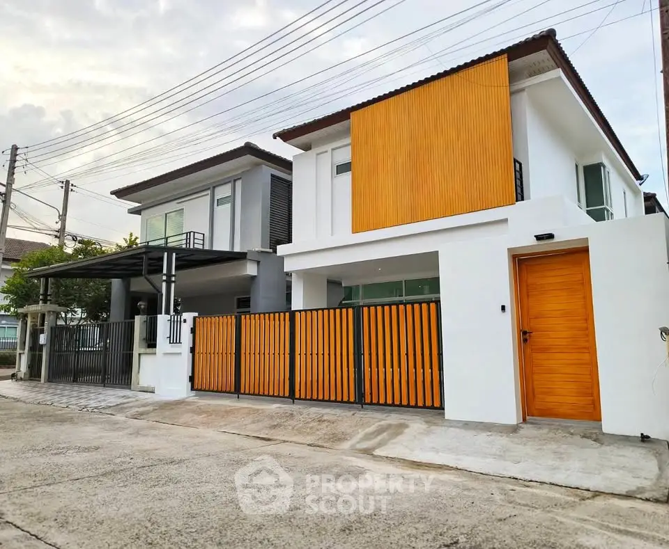 Modern two-story house with sleek design and wooden accents in a suburban neighborhood.