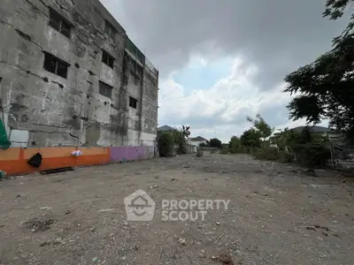 Spacious vacant lot beside a weathered building, ideal for development opportunities.