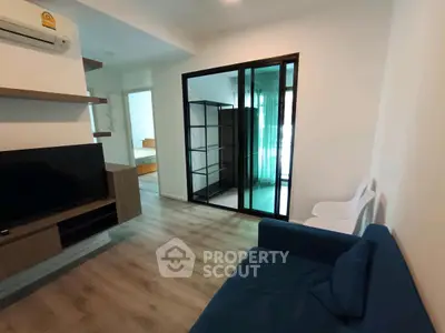 Modern living room with sleek design and sliding glass doors leading to a bedroom, featuring stylish furniture.