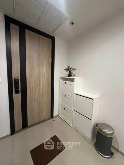 Modern apartment entrance with sleek wooden door and white storage cabinets