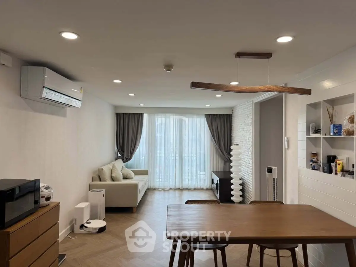 Modern living room with stylish furniture and natural light, featuring a cozy sofa and elegant dining area.
