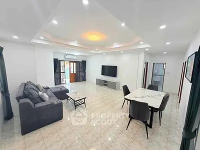 Spacious modern living room with elegant furniture and large TV, perfect for family gatherings.