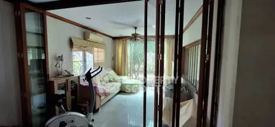 Cozy living room with natural light, featuring a comfortable sofa and exercise bike, perfect for relaxation and fitness.