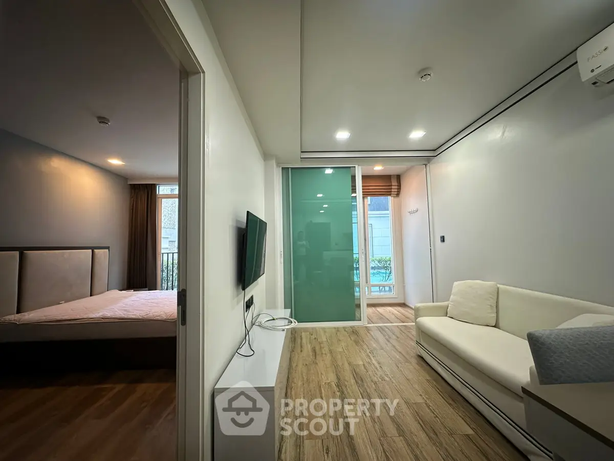 Modern apartment interior with living room and bedroom, featuring sleek design and wooden flooring.