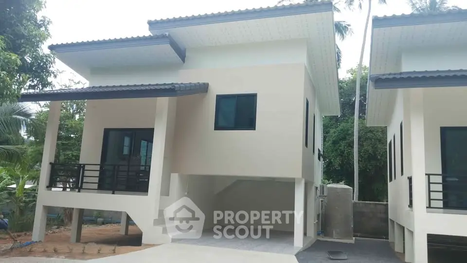 Modern two-story house with carport and sleek design in a lush green setting.