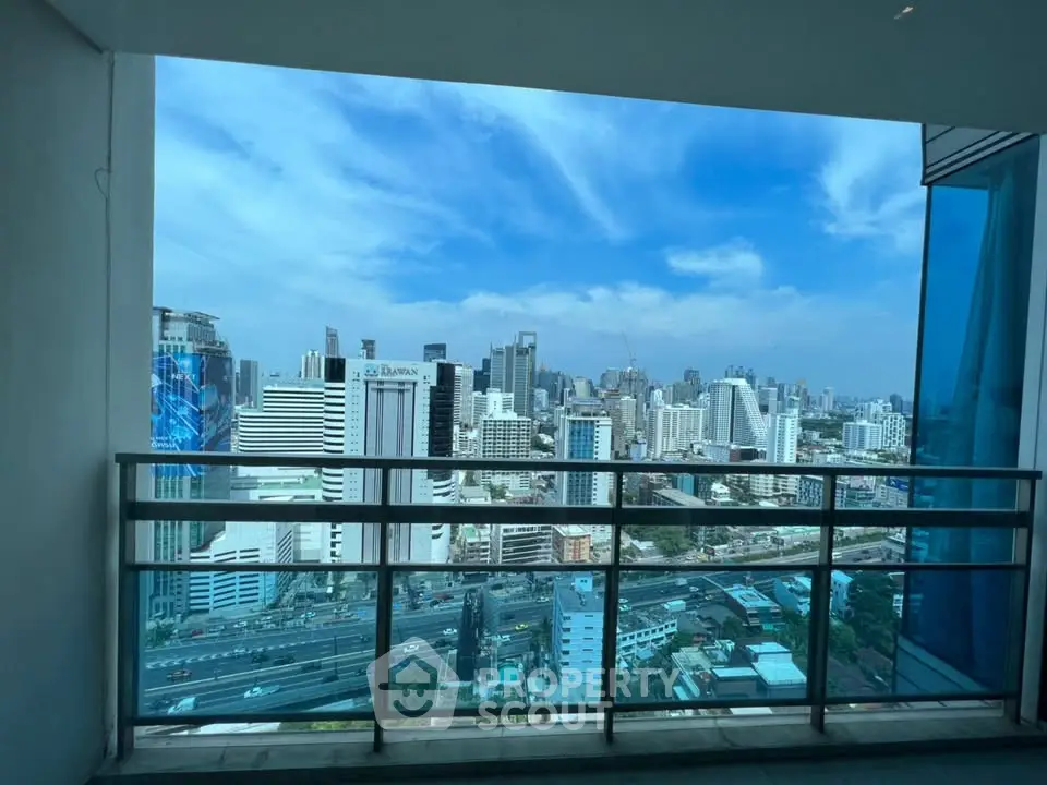 Stunning cityscape view from a high-rise balcony with clear blue skies.