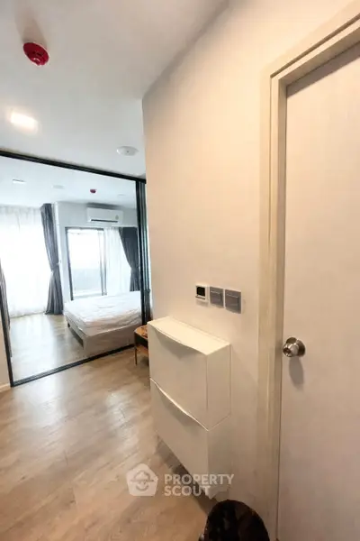 Modern apartment hallway leading to a cozy bedroom with natural light