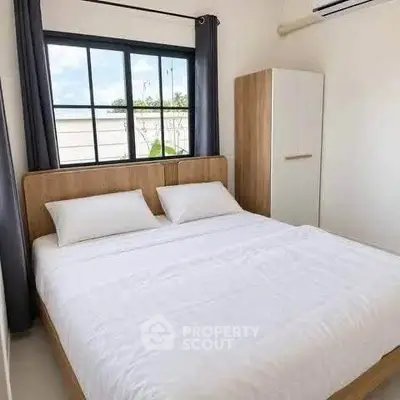 Cozy bedroom with modern furnishings and large window for natural light.