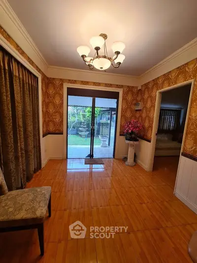 Elegant living room with wooden flooring and garden view, featuring classic chandelier and luxurious drapes.