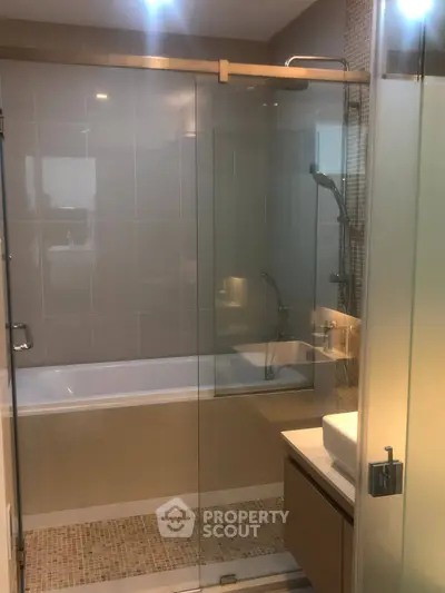 Modern bathroom with glass shower and bathtub in stylish apartment.