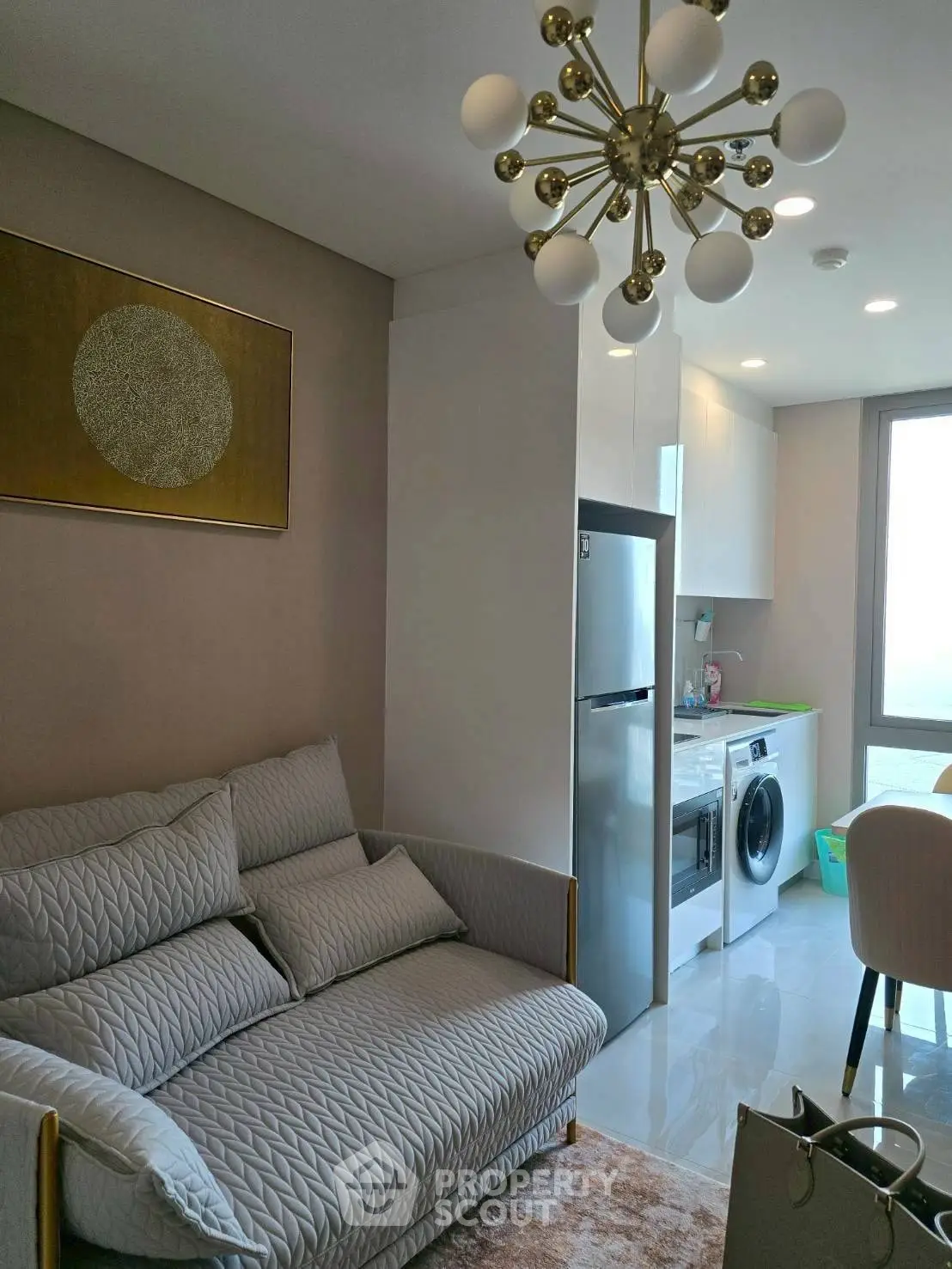 Modern living room with stylish decor and compact kitchen area featuring a washing machine.