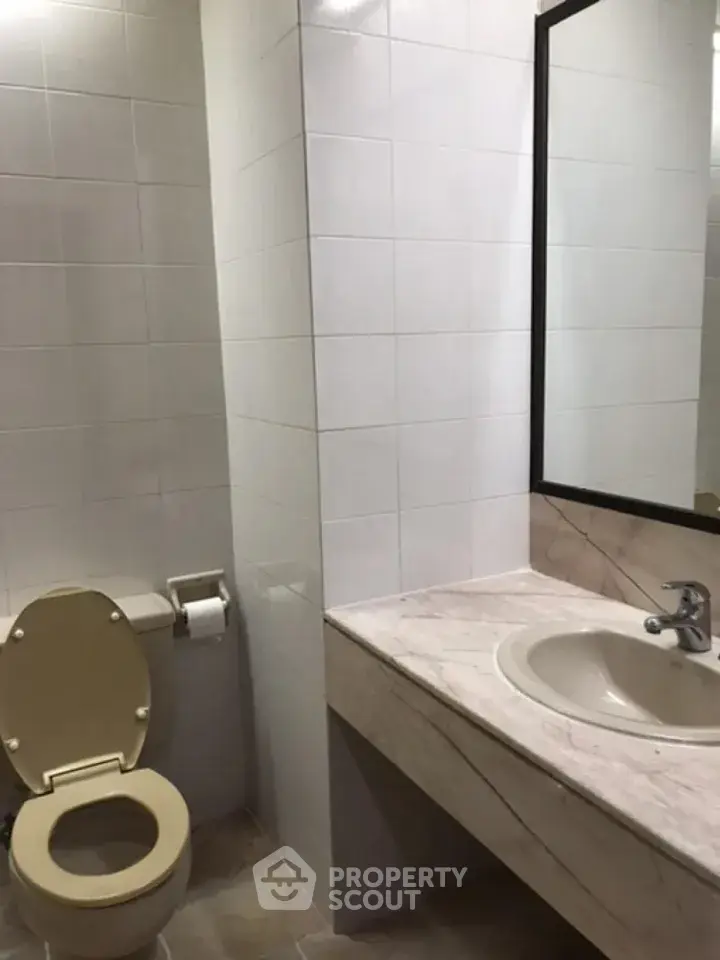 Modern bathroom with tiled walls and marble countertop in a real estate property.