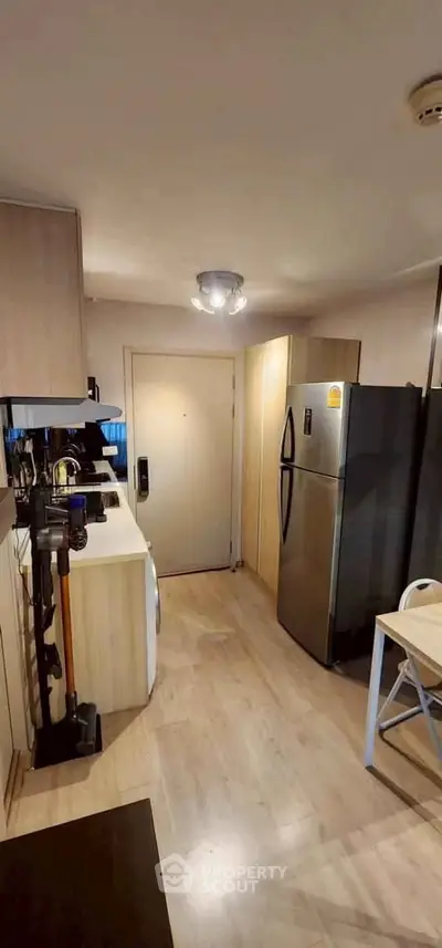 Modern kitchen with sleek appliances and wooden cabinetry, featuring a spacious fridge and contemporary lighting.