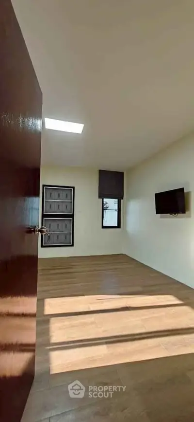 Spacious room with wooden flooring and wall-mounted TV, ideal for modern living.