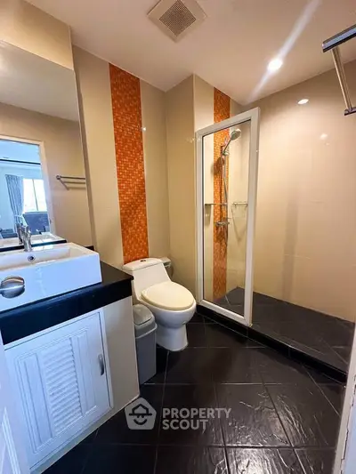 Modern bathroom with glass shower and stylish orange tile accents
