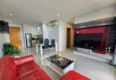 Modern living room with red sofa, sleek TV unit, and open kitchen layout in stylish apartment.