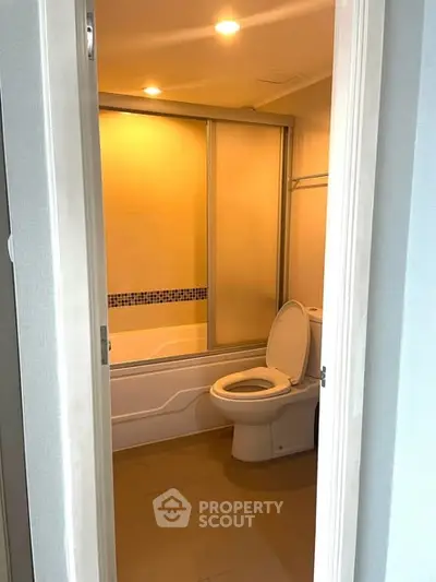 Modern bathroom with bathtub and toilet in a cozy apartment setting.