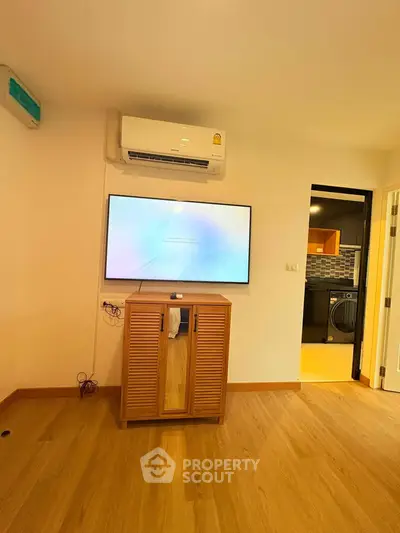 Modern living room with air conditioning and wall-mounted TV, featuring wooden flooring and stylish decor.