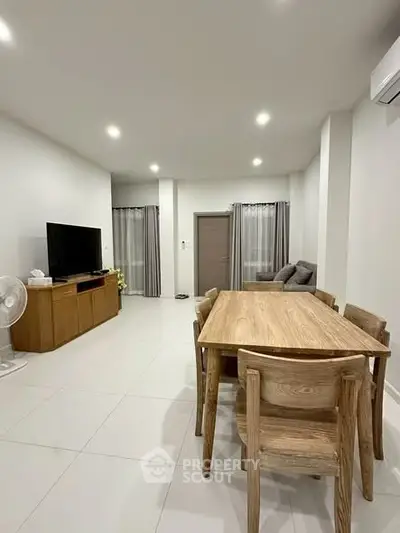 Spacious modern living room with wooden dining set and TV unit, perfect for family gatherings.