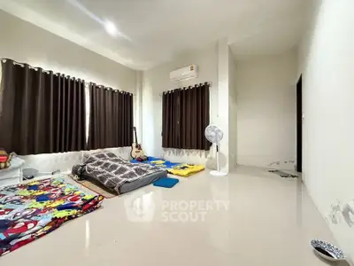 Spacious bedroom with large windows and minimalistic decor, featuring air conditioning and natural light.