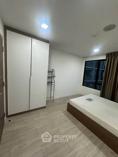 Modern bedroom with minimalist design and large window offering natural light.