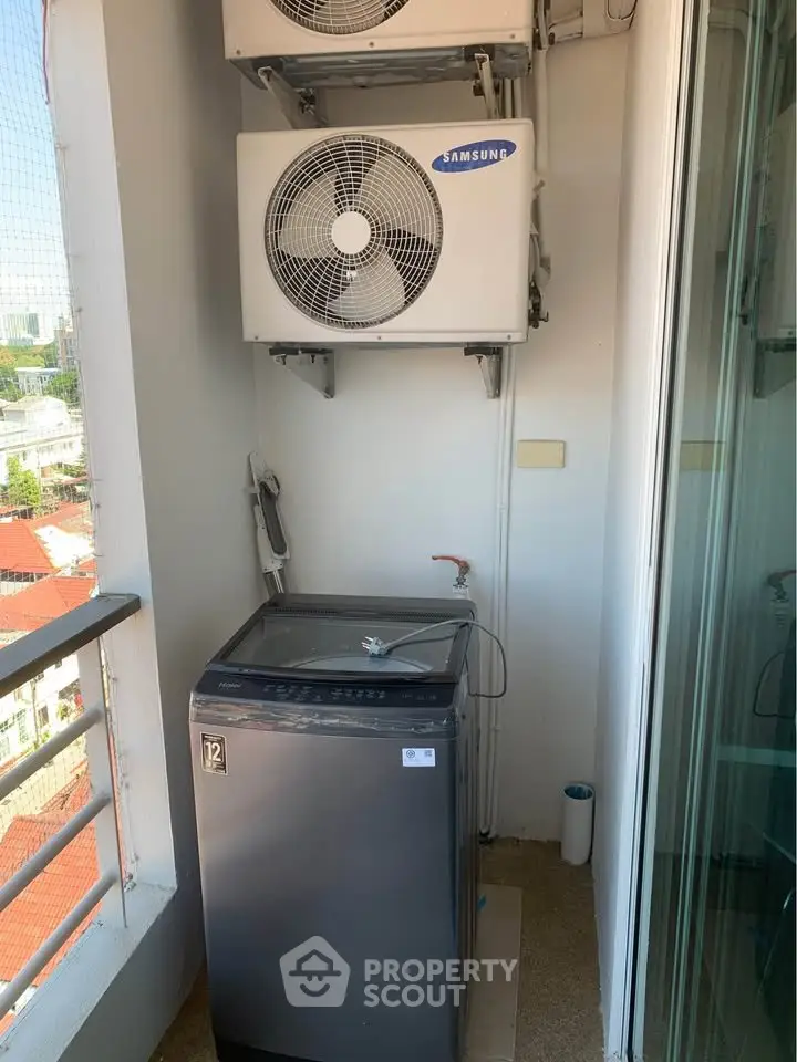 Compact balcony with washing machine and air conditioning units in urban apartment.