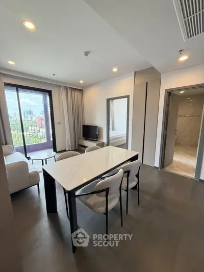 Modern open-plan living room with dining area and city view balcony in luxury apartment.