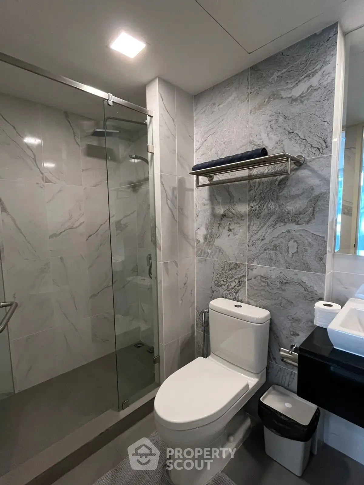 Modern bathroom with sleek design, featuring glass shower and elegant marble tiles.