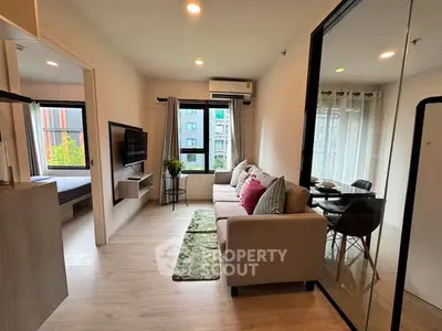 Modern living room with cozy sofa, wall-mounted TV, and dining area in a bright apartment.