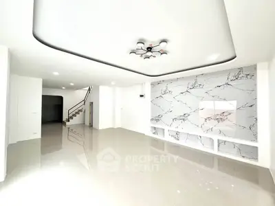 Spacious modern living room with elegant marble accent wall and stylish ceiling light fixture.