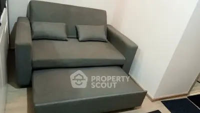 Compact gray sofa bed in a cozy living room corner, perfect for small spaces.