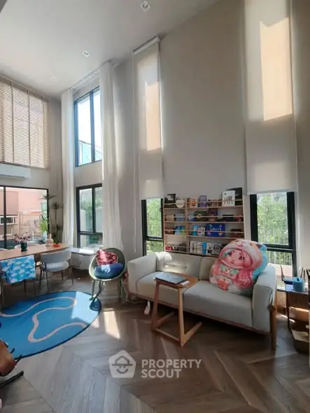 Spacious living room with high ceilings, large windows, and modern decor in a stylish home.