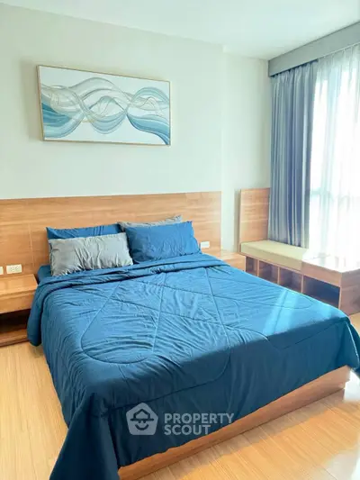 Modern bedroom with blue bedding and stylish artwork, featuring natural light and wooden accents.