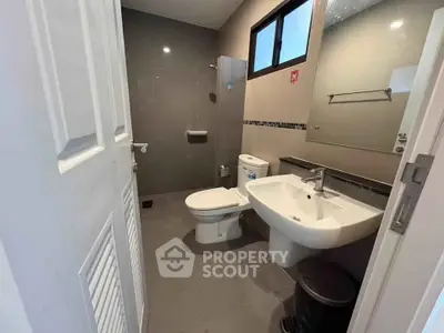 Modern bathroom with sleek fixtures and neutral tones, featuring a pedestal sink and large mirror.