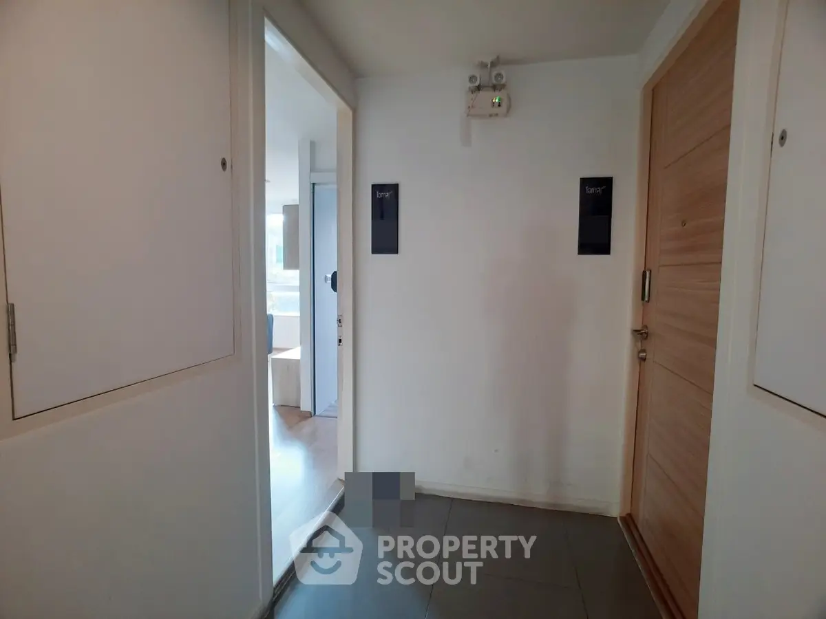 Modern apartment entrance with sleek wooden doors and bright hallway lighting.