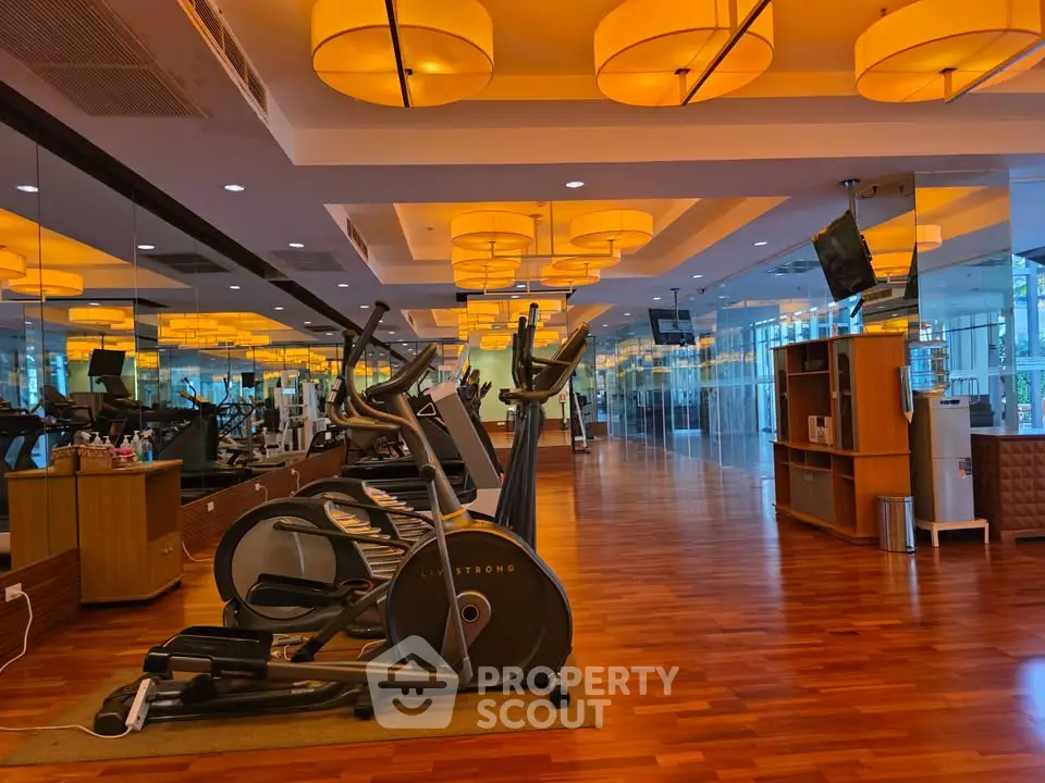 Spacious modern gym with wooden flooring and stylish lighting in a luxury residential building.